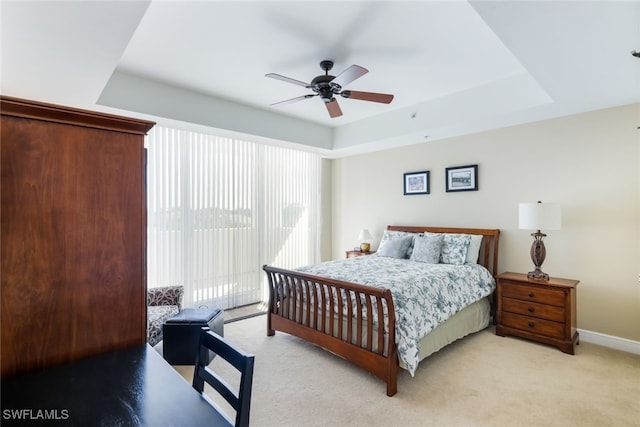 carpeted bedroom with ceiling fan and a tray ceiling