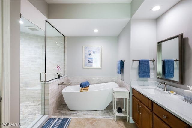 bathroom with tile patterned floors, vanity, independent shower and bath, and tile walls