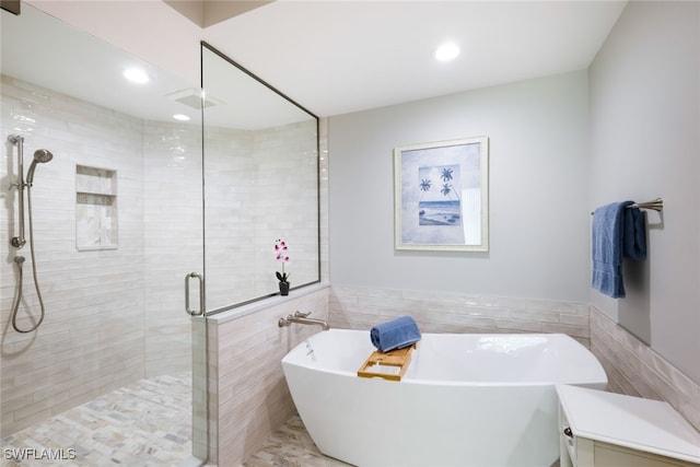 bathroom with tile walls and independent shower and bath