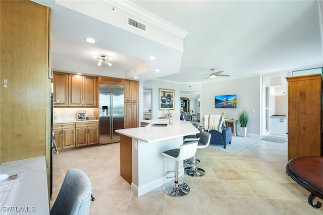 kitchen with ceiling fan, sink, tasteful backsplash, stainless steel built in refrigerator, and a kitchen bar