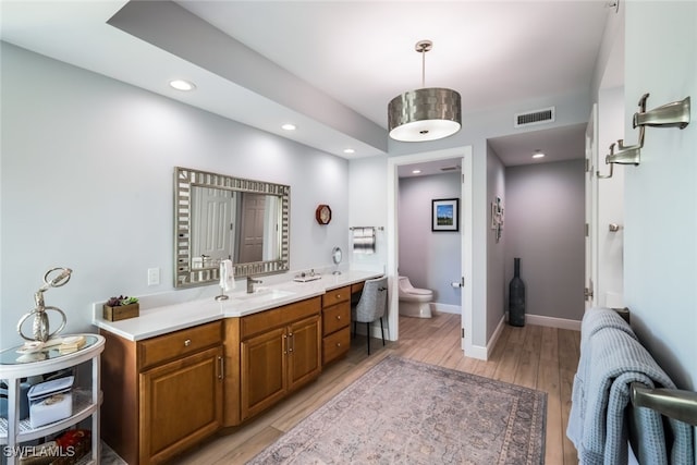 bathroom with hardwood / wood-style flooring, vanity, and toilet