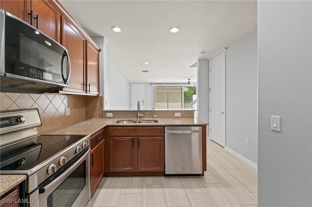 kitchen featuring sink, appliances with stainless steel finishes, kitchen peninsula, light stone countertops, and decorative backsplash