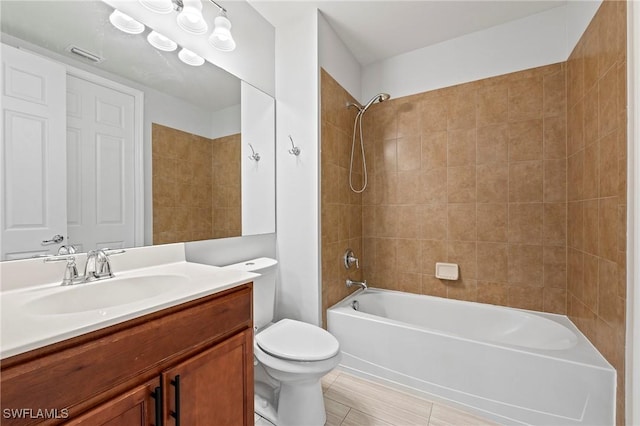 full bathroom featuring tiled shower / bath, vanity, and toilet