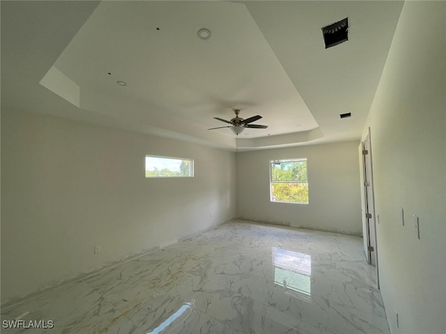 empty room featuring a tray ceiling and ceiling fan