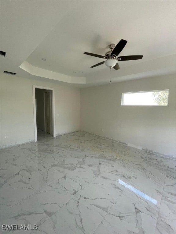 empty room featuring ceiling fan and a tray ceiling