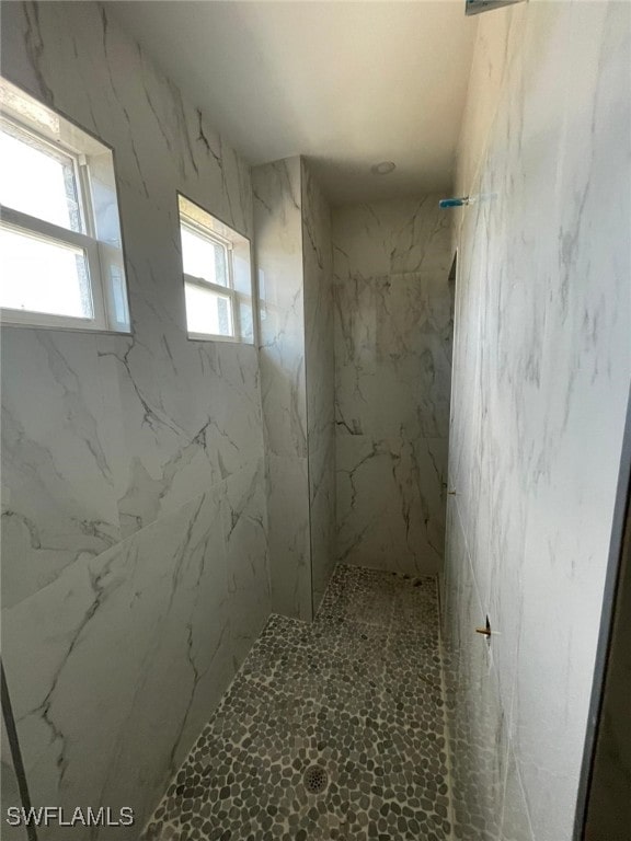 bathroom featuring tiled shower and a wealth of natural light