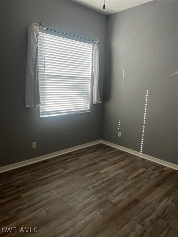 unfurnished room featuring a wealth of natural light and dark wood-type flooring