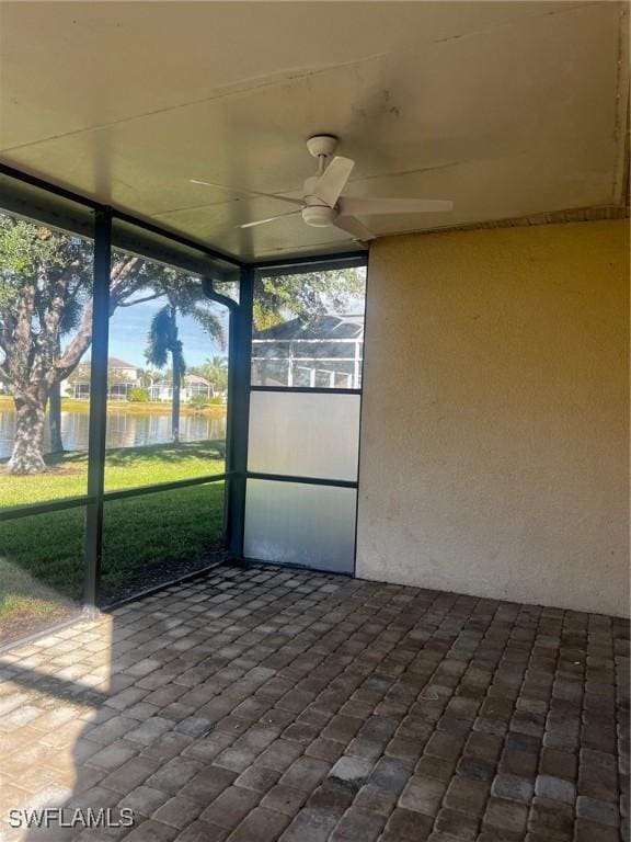 unfurnished sunroom featuring a water view and ceiling fan