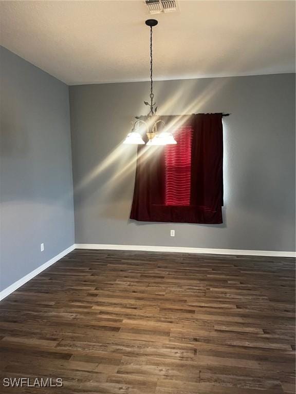 unfurnished dining area featuring a chandelier and dark wood-type flooring