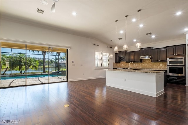 kitchen with decorative light fixtures, dark hardwood / wood-style floors, crown molding, and an island with sink