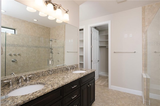 bathroom with tile patterned flooring, vanity, and a tile shower