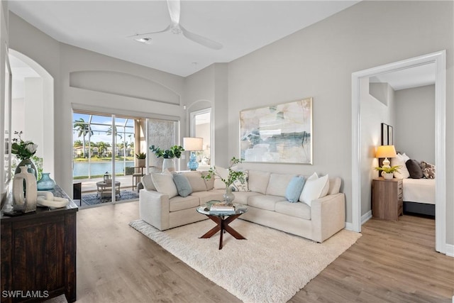 living room with ceiling fan, a water view, and light hardwood / wood-style flooring