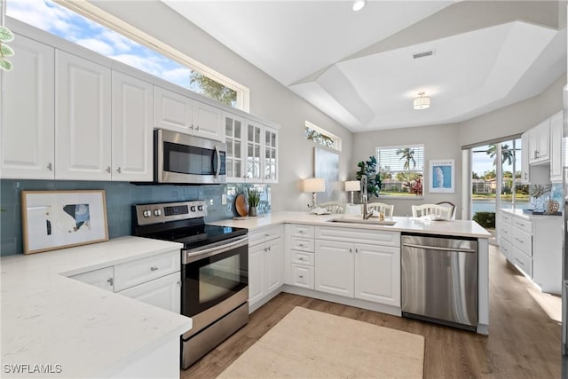 kitchen with white cabinets, sink, tasteful backsplash, kitchen peninsula, and stainless steel appliances