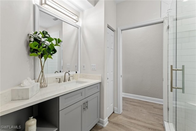 bathroom featuring hardwood / wood-style flooring, vanity, and walk in shower