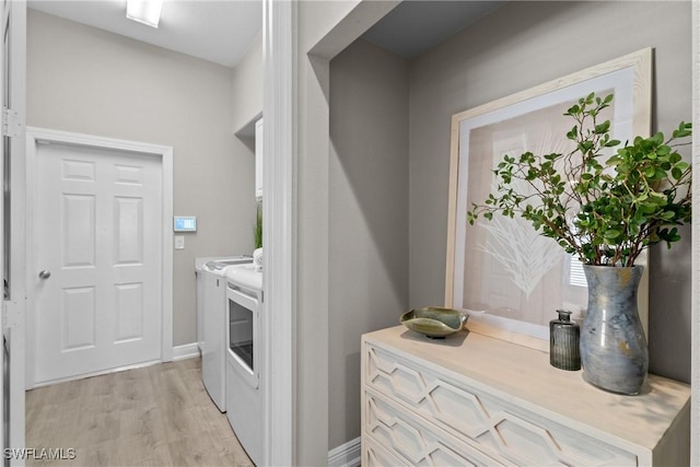 laundry area with washing machine and clothes dryer and light hardwood / wood-style floors