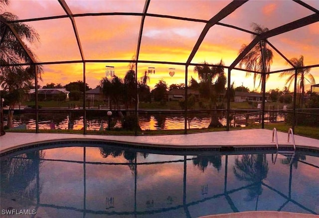 pool at dusk featuring a lanai and a water view