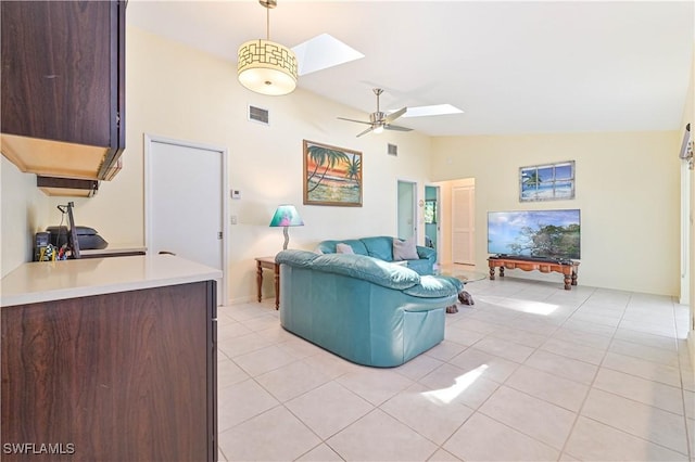 tiled living room with lofted ceiling with skylight and ceiling fan