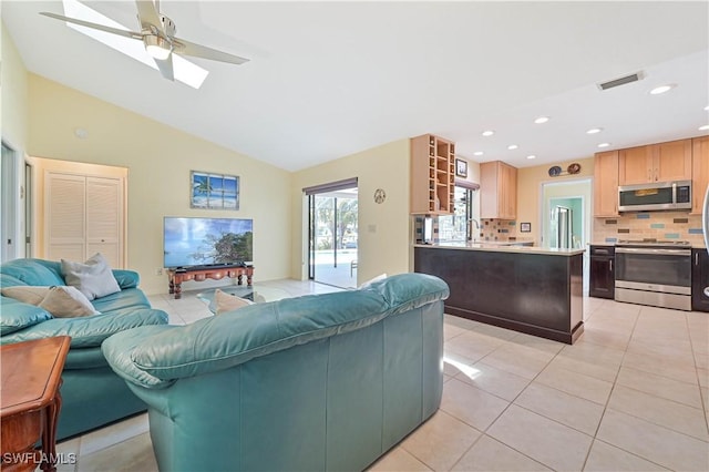 living room featuring light tile patterned floors, ceiling fan, lofted ceiling, and sink