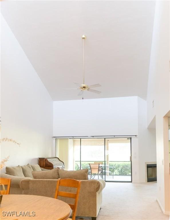 carpeted living room with ceiling fan and a towering ceiling