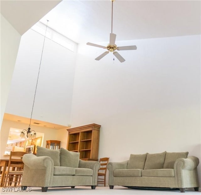 living room with ceiling fan with notable chandelier and a towering ceiling