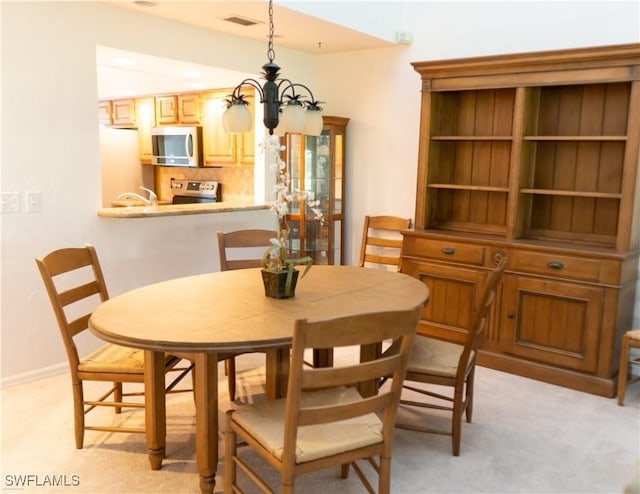 dining area with light colored carpet and a chandelier