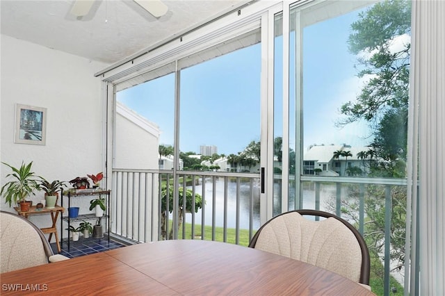 sunroom featuring ceiling fan and a water view