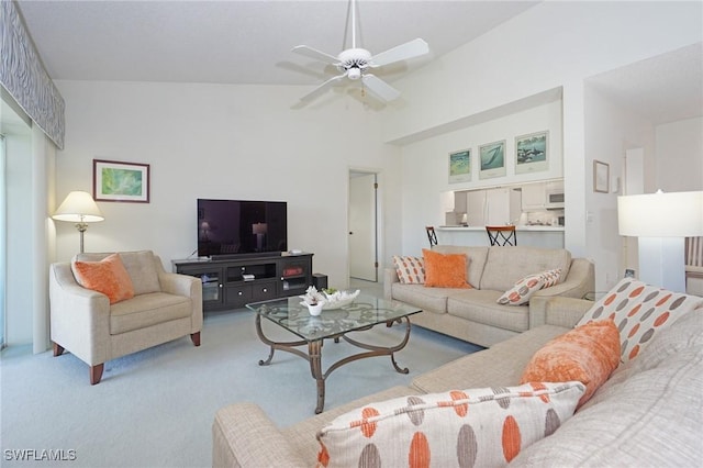 carpeted living room with ceiling fan and high vaulted ceiling