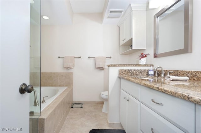 bathroom featuring tile patterned floors, vanity, tiled bath, and toilet