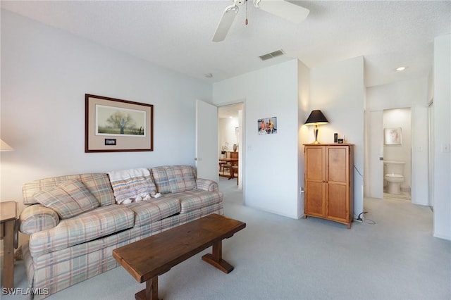 carpeted living room featuring a textured ceiling and ceiling fan