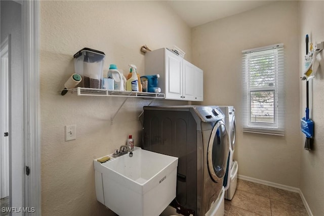 laundry area featuring washer and clothes dryer, cabinets, light tile patterned floors, and sink