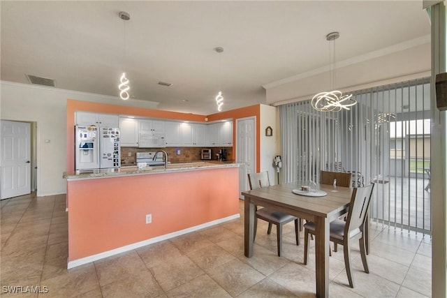 tiled dining space featuring ornamental molding, sink, and a chandelier