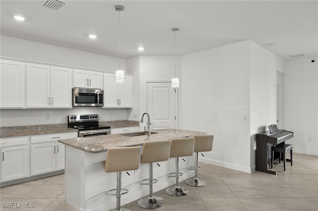 kitchen with sink, stainless steel appliances, an island with sink, pendant lighting, and white cabinets