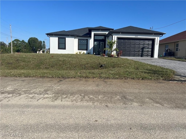 view of front of property featuring decorative driveway, an attached garage, a front yard, and stucco siding