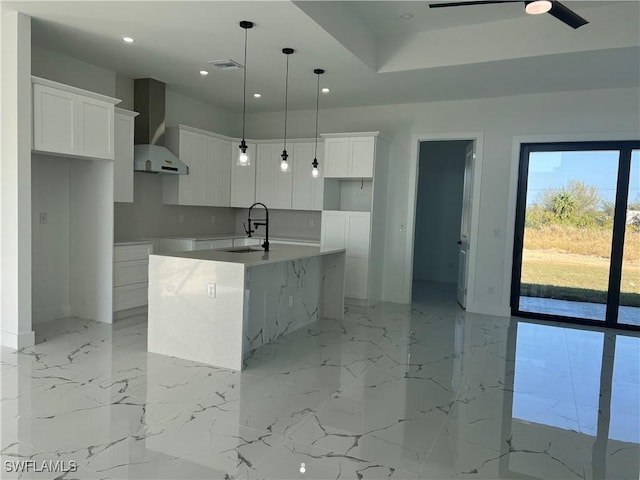 kitchen featuring marble finish floor, white cabinetry, a center island with sink, and hanging light fixtures