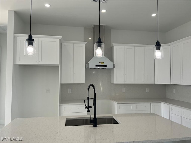 kitchen with light stone countertops, white cabinetry, and pendant lighting