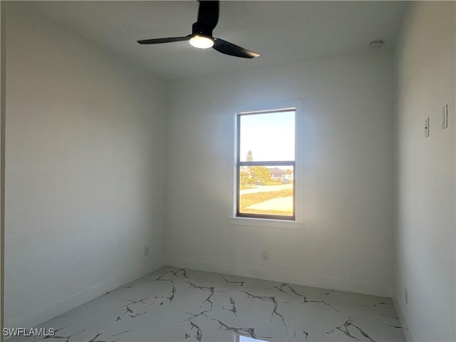 unfurnished room featuring ceiling fan, marble finish floor, and baseboards