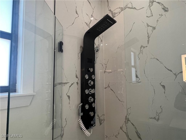 interior details featuring a marble finish shower