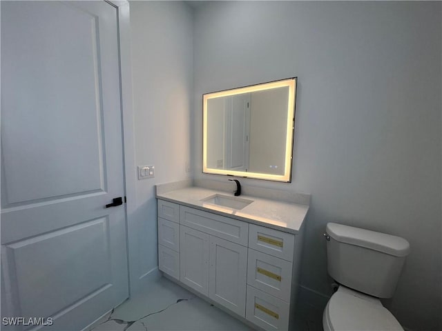 half bathroom featuring marble finish floor, vanity, and toilet