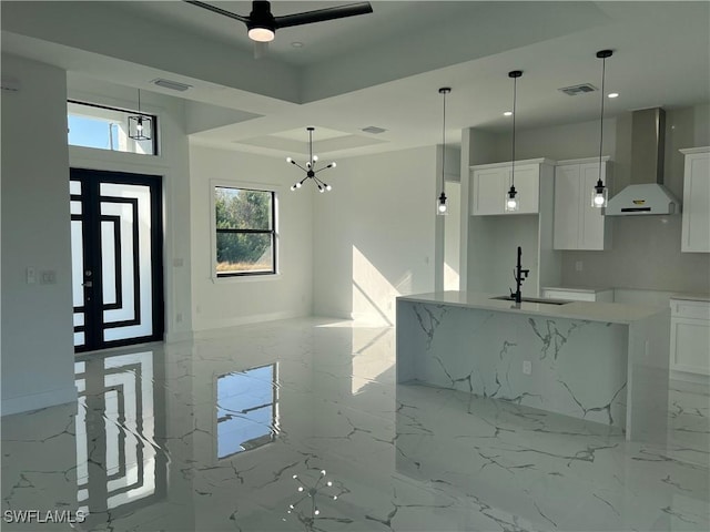 kitchen with white cabinets, a center island with sink, wall chimney exhaust hood, and sink