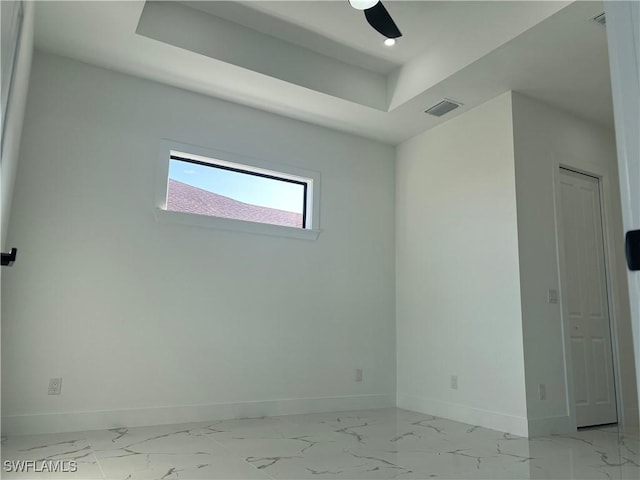 unfurnished room featuring a tray ceiling, marble finish floor, visible vents, and baseboards