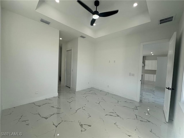 spare room with a tray ceiling and ceiling fan