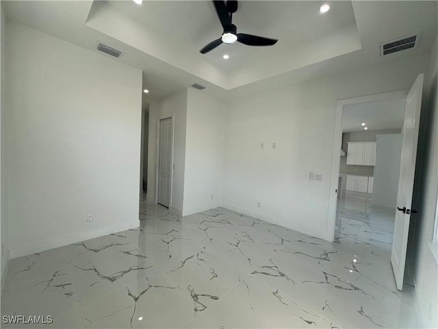 empty room featuring a raised ceiling and ceiling fan