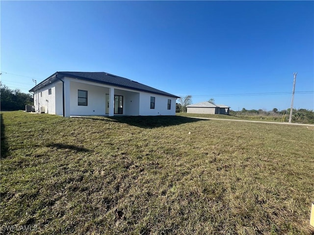 view of front of home with a front lawn, central AC, and stucco siding