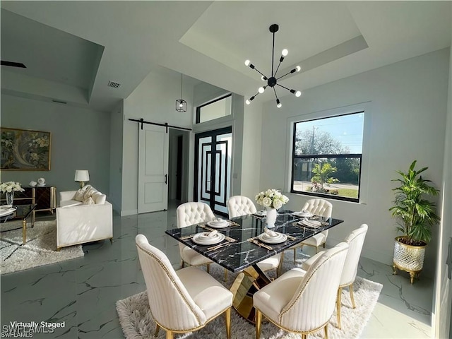 dining area with marble finish floor, a barn door, visible vents, and a tray ceiling