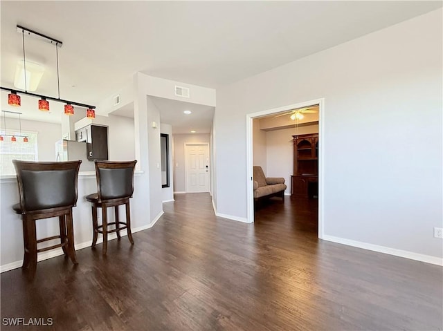 interior space featuring kitchen peninsula, dark hardwood / wood-style floors, ceiling fan, and a breakfast bar area