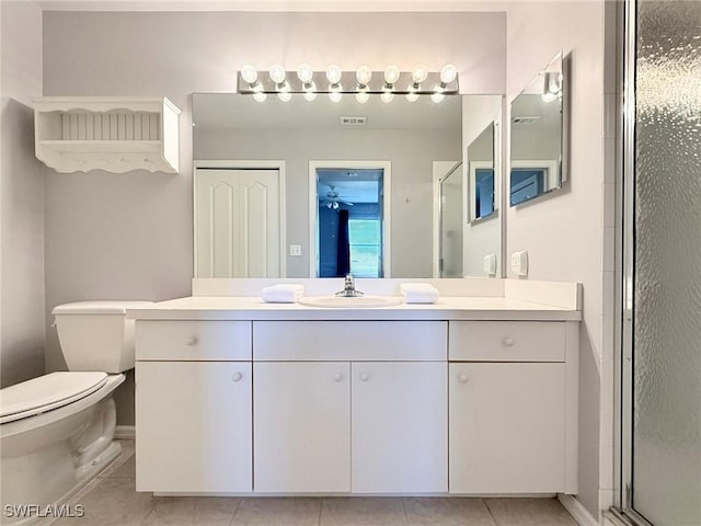 bathroom with tile patterned flooring, vanity, toilet, and a shower with door