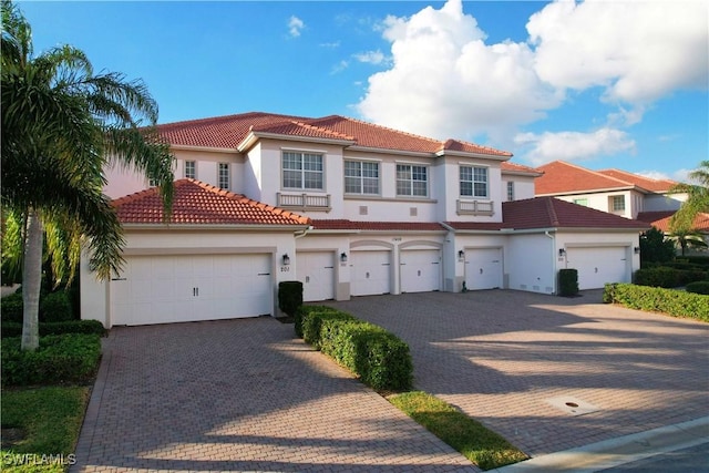 mediterranean / spanish house featuring decorative driveway, a tile roof, and stucco siding