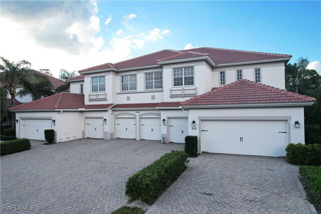 mediterranean / spanish-style house with stucco siding, decorative driveway, and a tiled roof