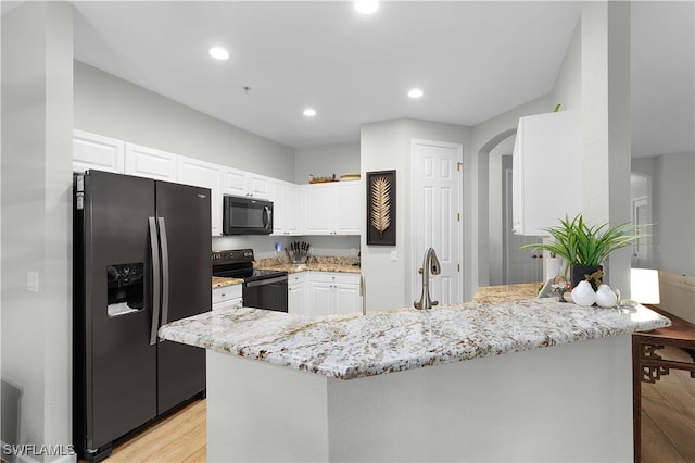 kitchen featuring black appliances, light wood-type flooring, white cabinetry, and light stone counters