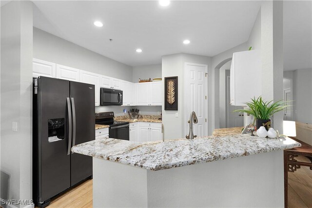 kitchen featuring arched walkways, black appliances, light stone countertops, and white cabinets